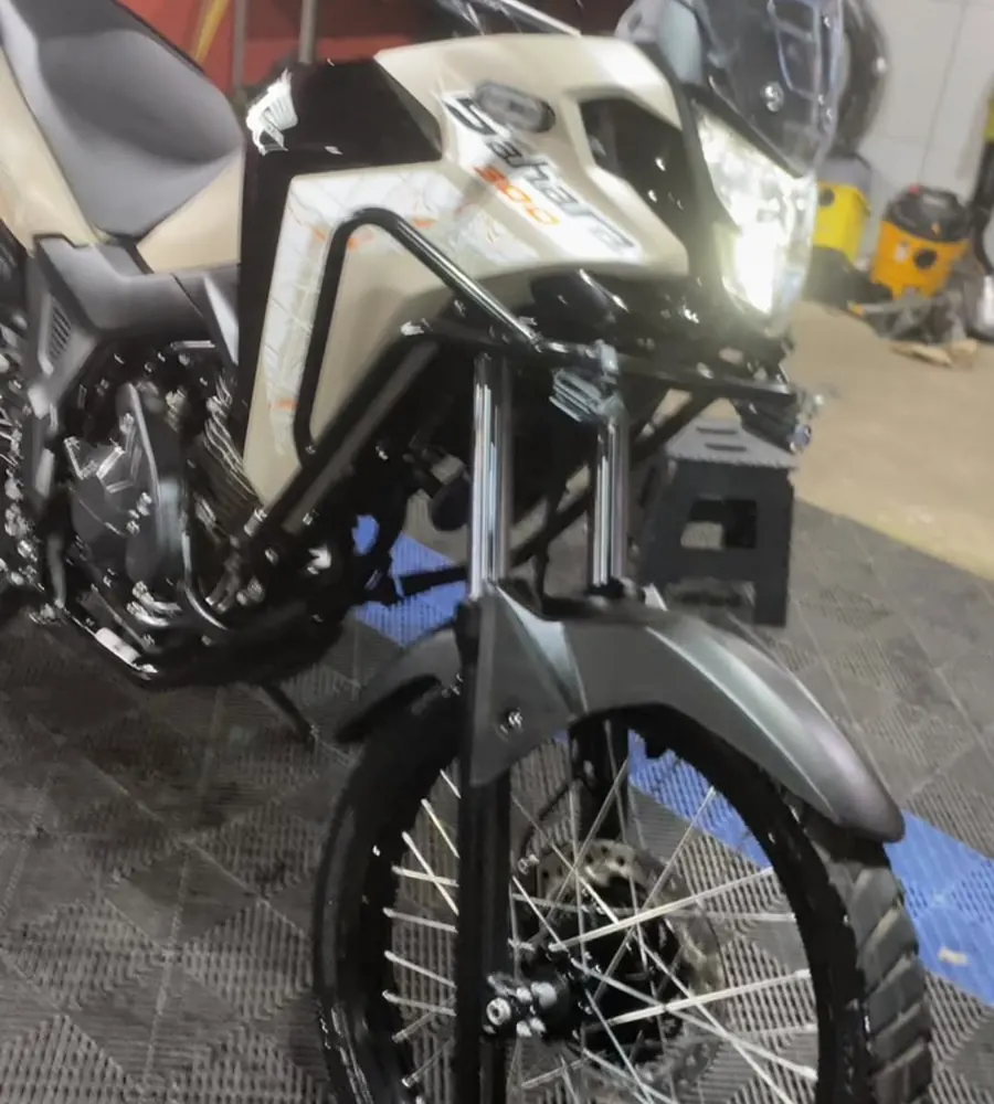 Honda XRE branca sobre o piso quadriculado da oficina
